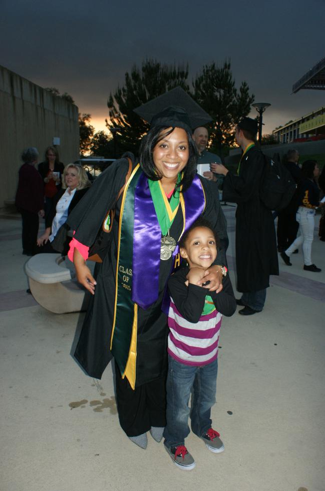  A student in her graduation attire with a child.