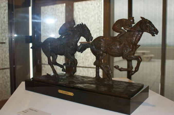  An art piece of two horses with riders on top of them.