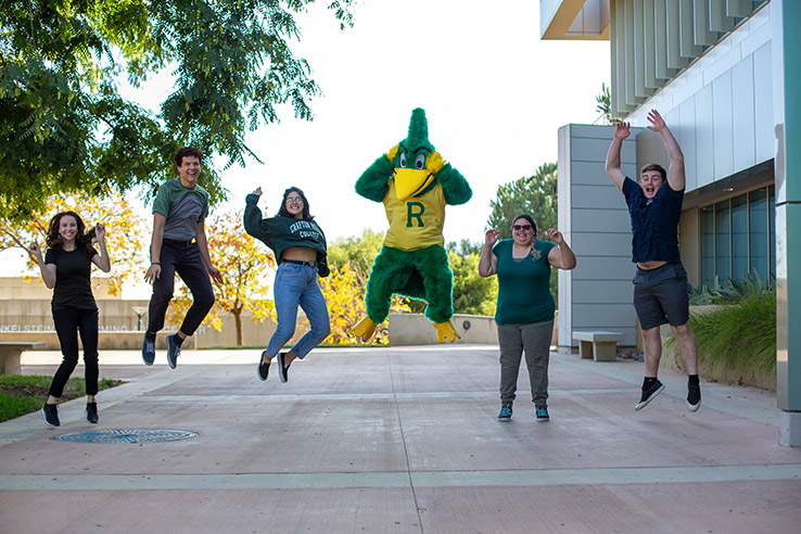 Students and roadrunner mascot jumping