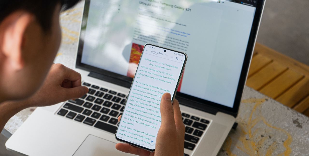 Person looking at a smartphone and laptop screen