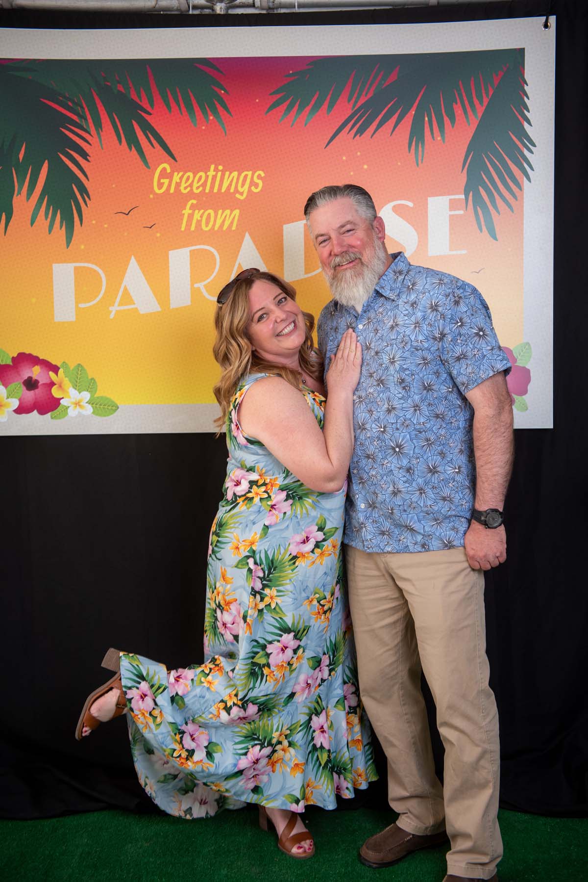 Two people in front of Greetings from Paradise sign