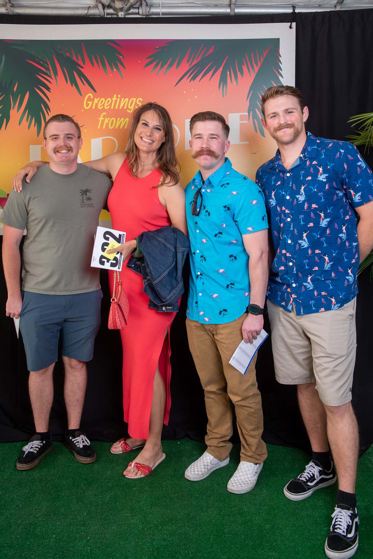 Four people in front of Greetings from Paradise sign