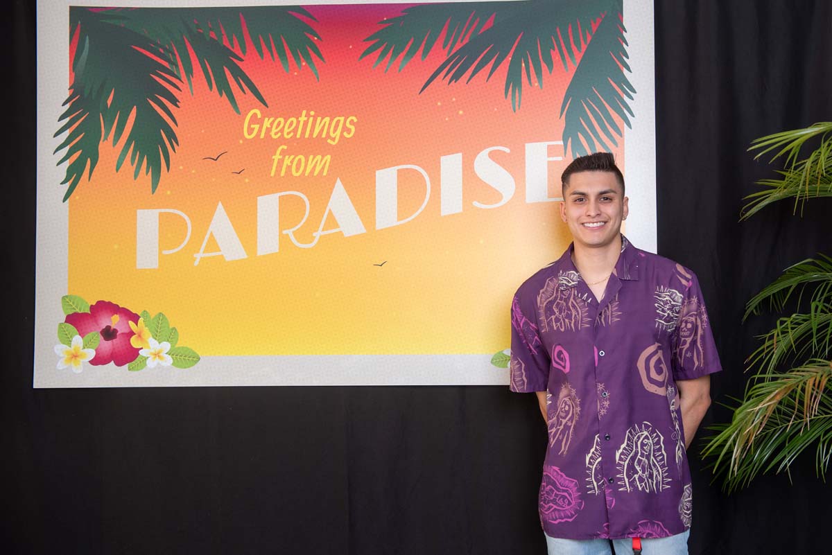 Person in front of Greetings from Paradise sign