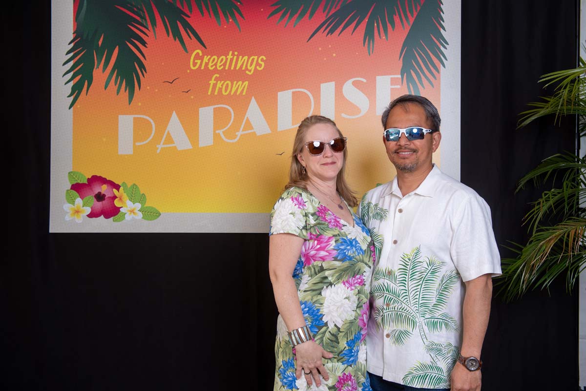 Two people in front of Greetings from Paradise sign