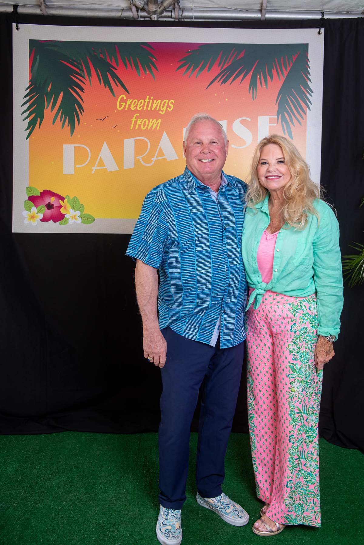 Two people in front of Greetings from Paradise sign