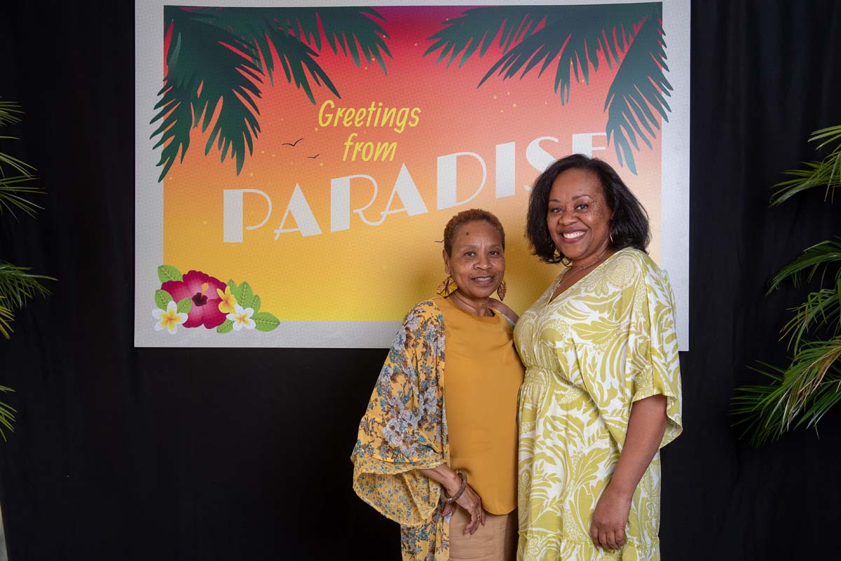 Two people in front of Greetings from Paradise sign