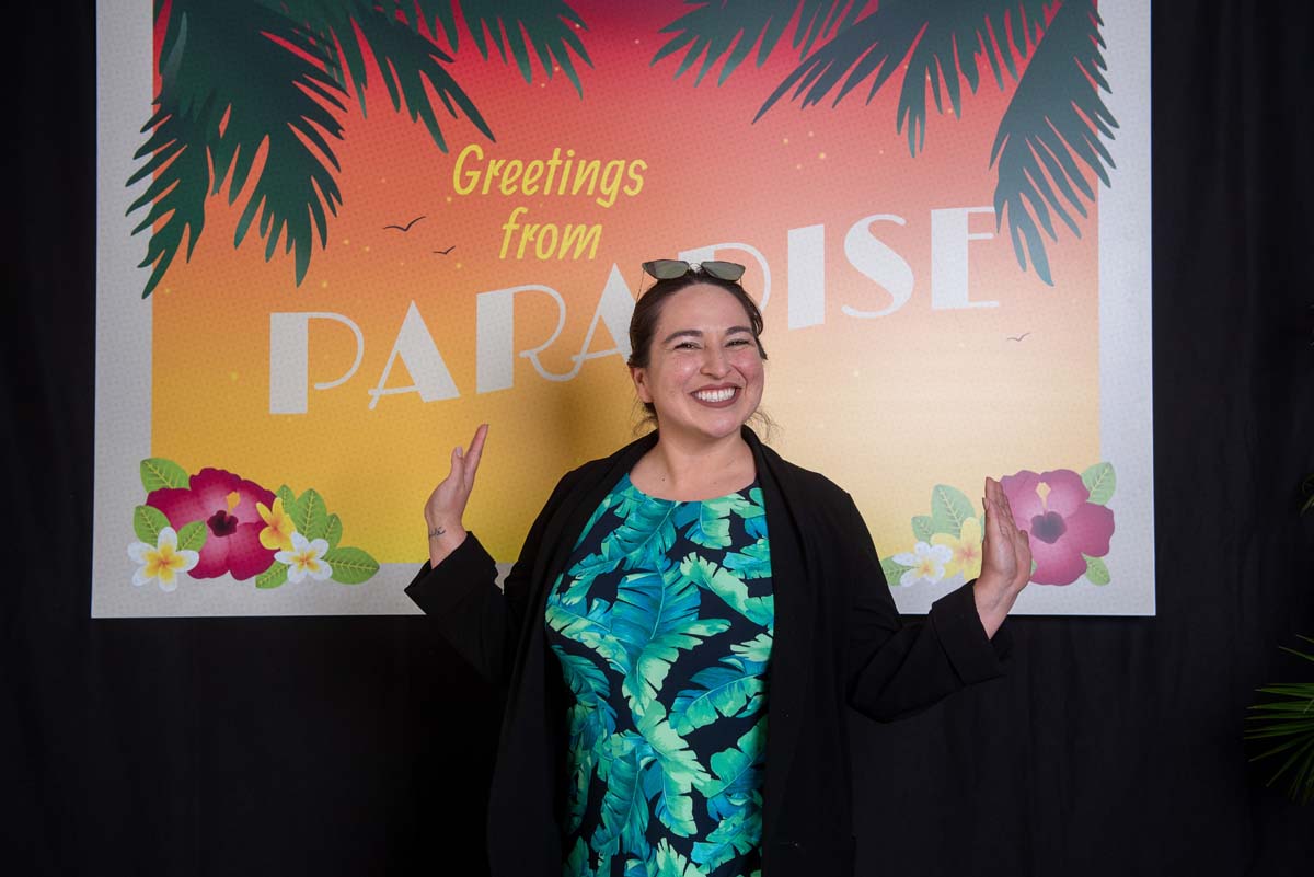 Person in front of Greetings from Paradise sign