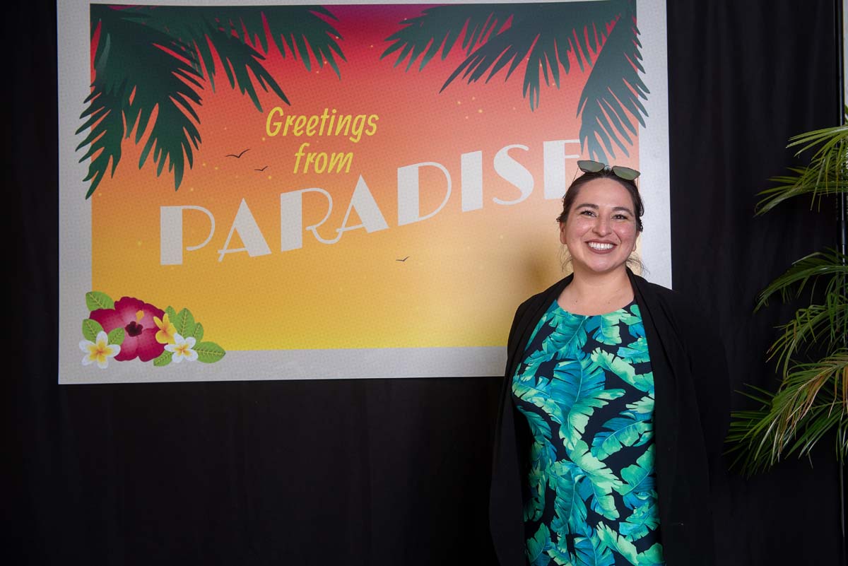 Person in front of Greetings from Paradise sign