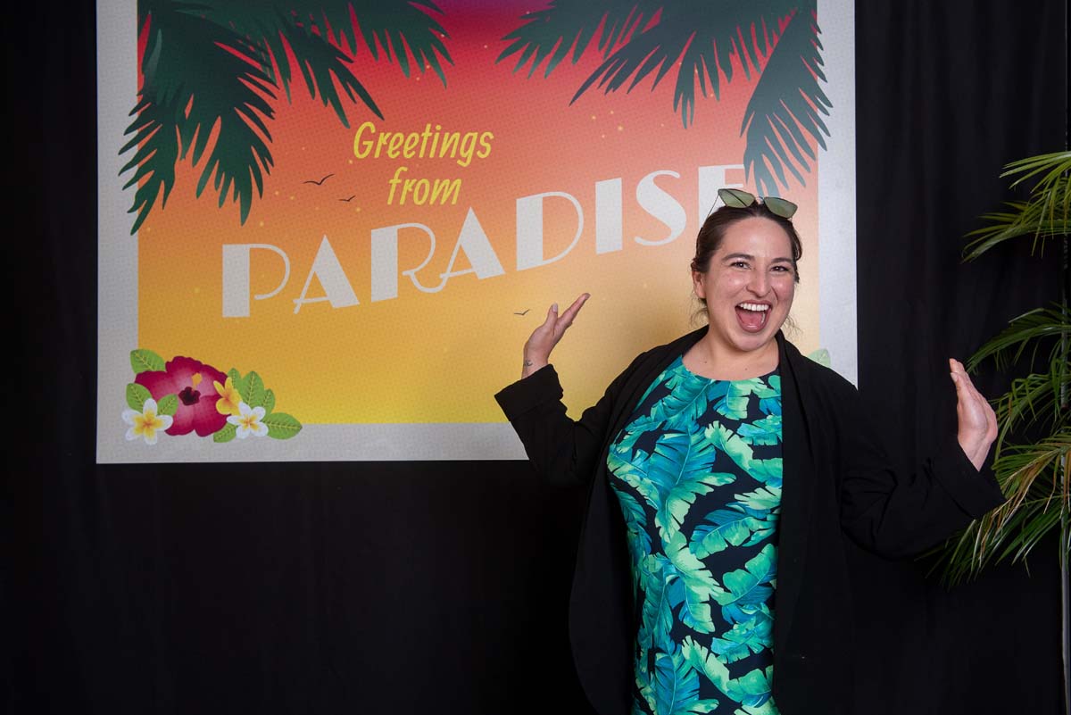 Person in front of Greetings from Paradise sign