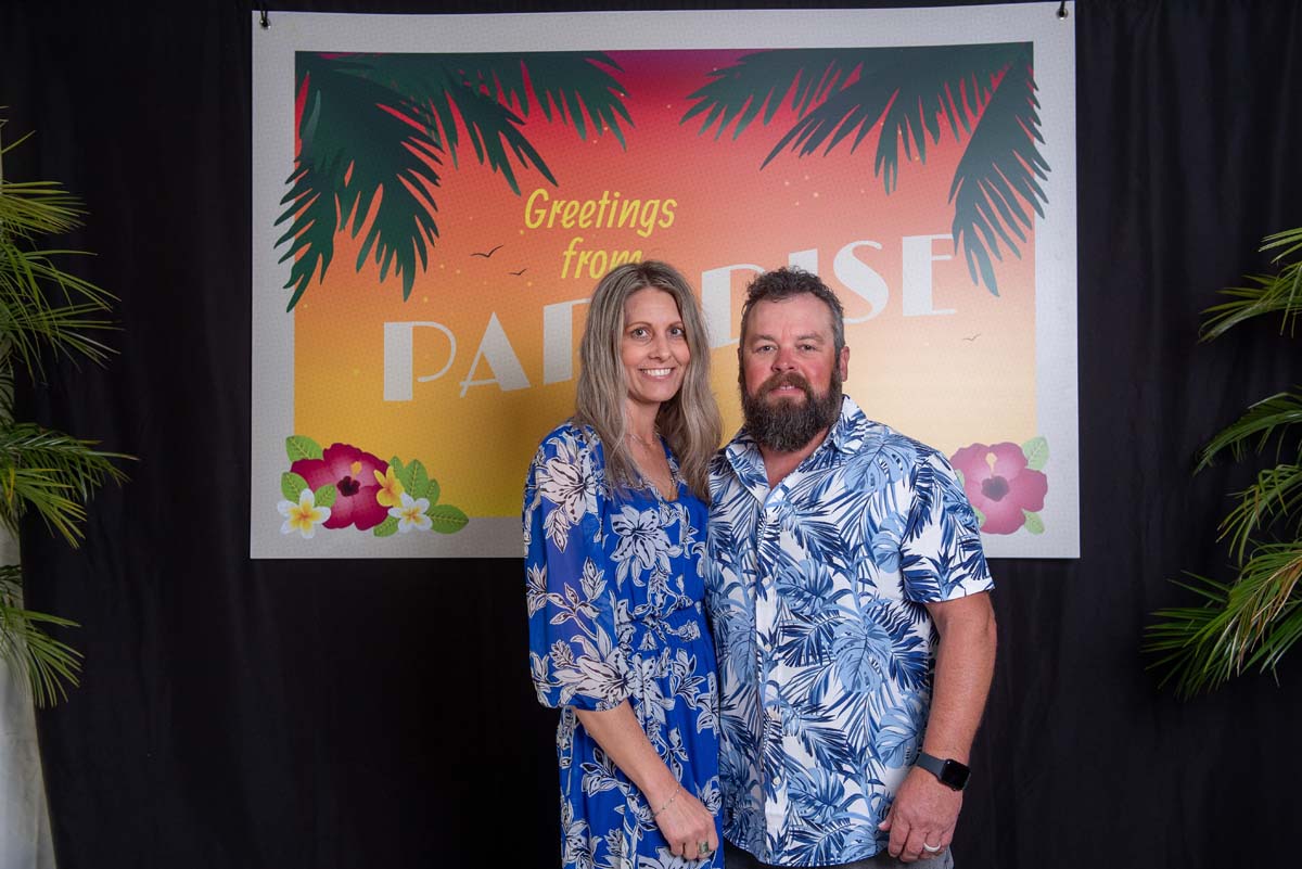 Two people in front of Greetings from Paradise sign