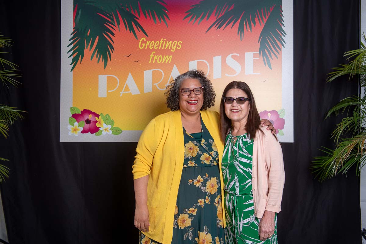Two women in front of Greetings from Paradise sign