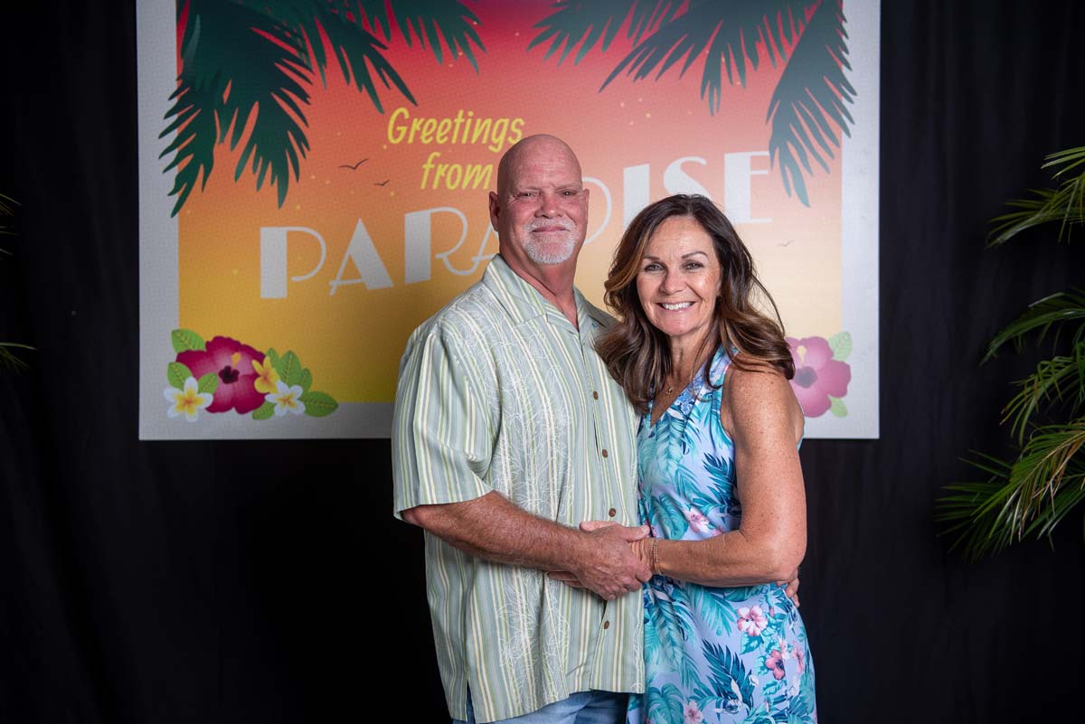 Two people in front of Greetings from Paradise sign