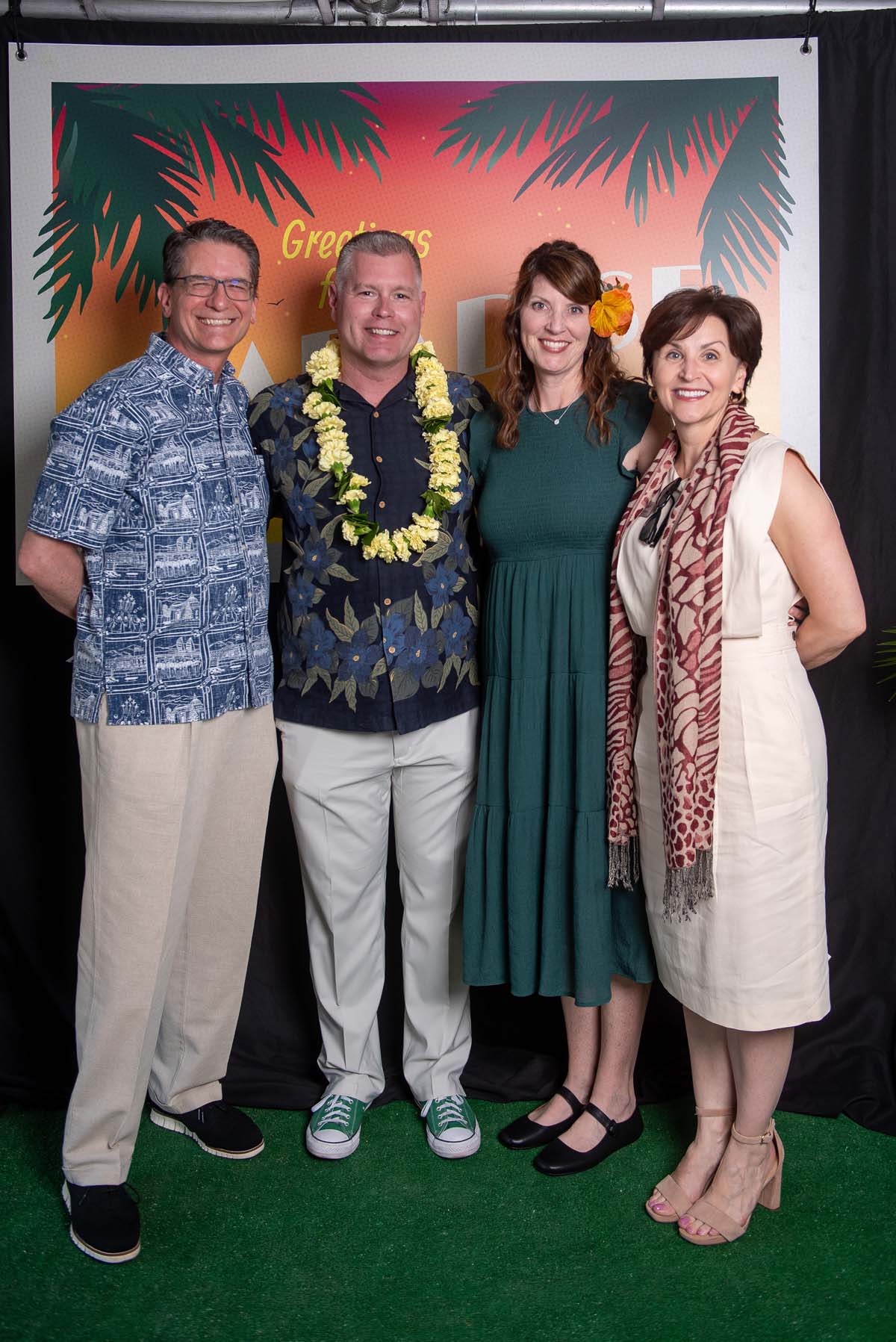 Four people in front of Greetings from Paradise sign