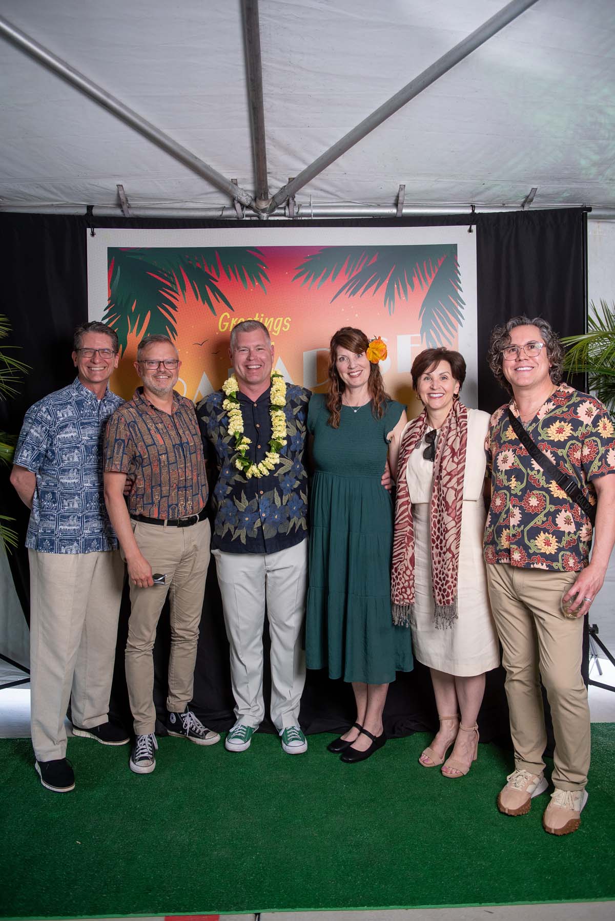 Six people in front of Greetings from Paradise sign