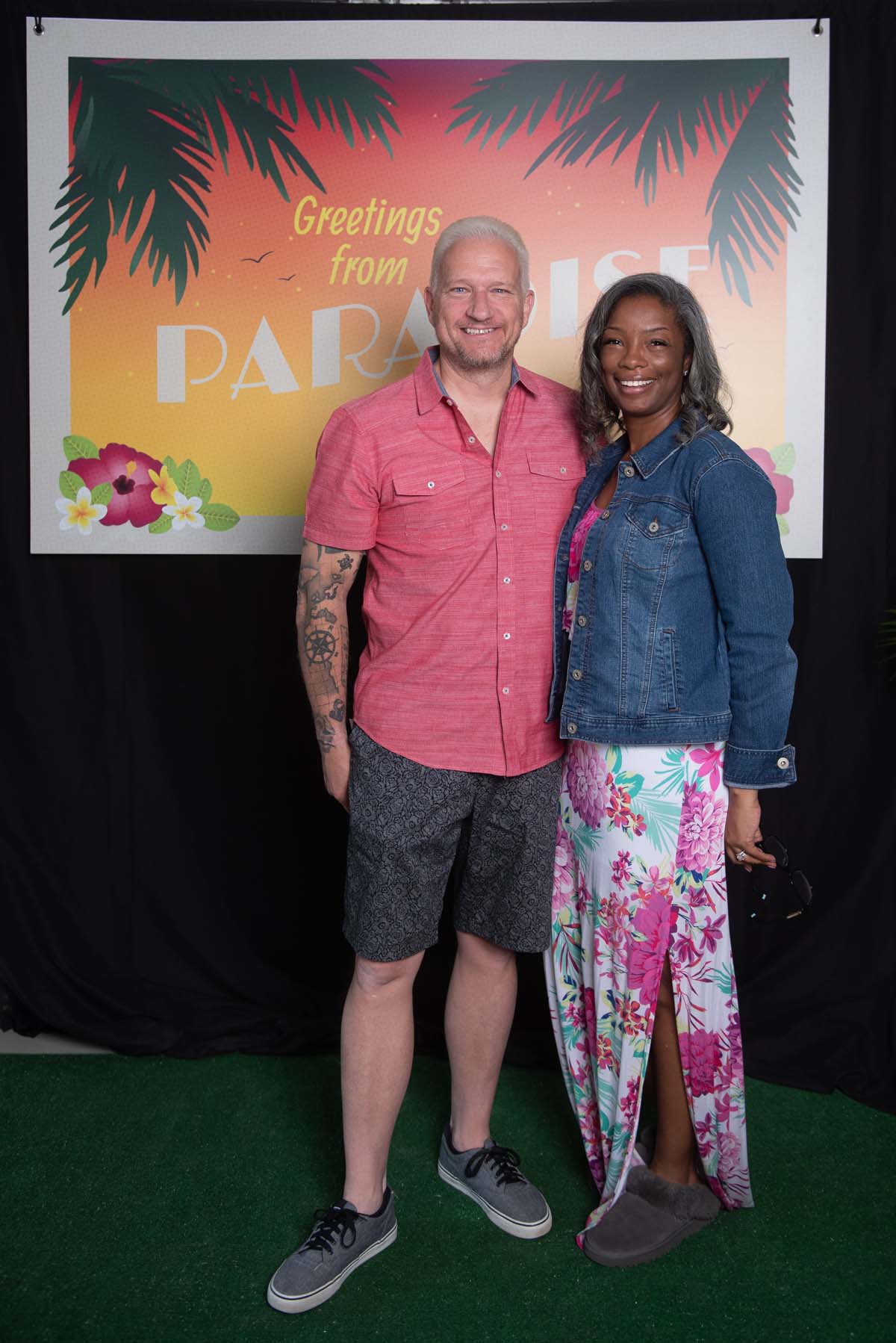 Two people in front of Greetings from Paradise sign