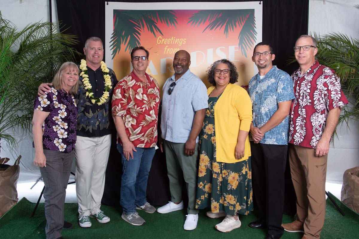 Group of people in front of Greetings from Paradise sign