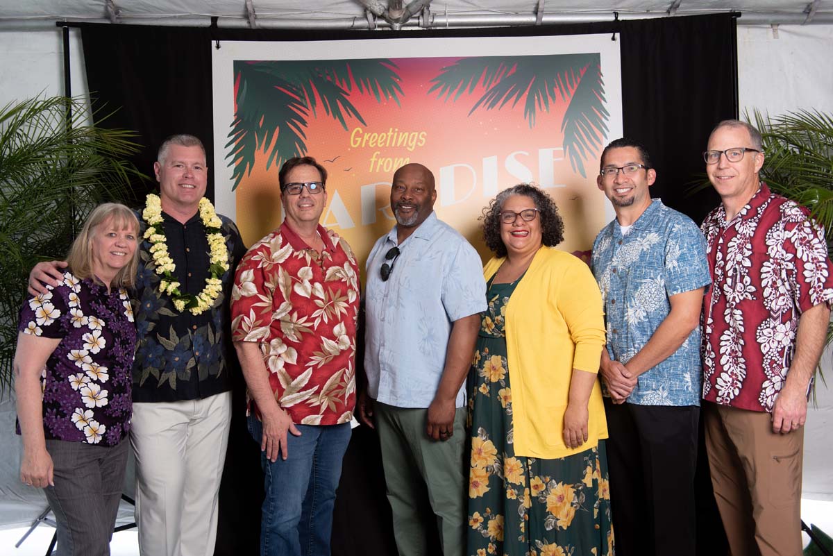 Group of people in front of Greetings from Paradise sign