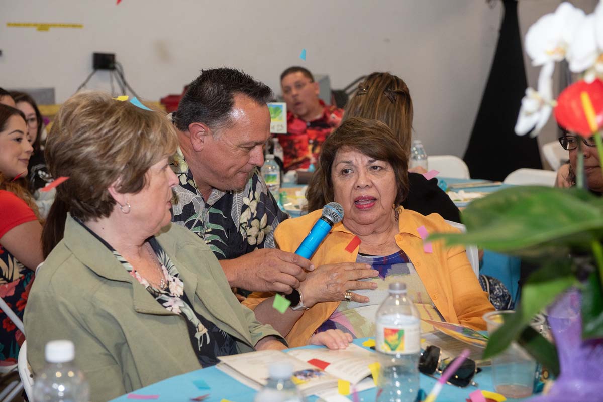 Man offering a mic to a woman at a table