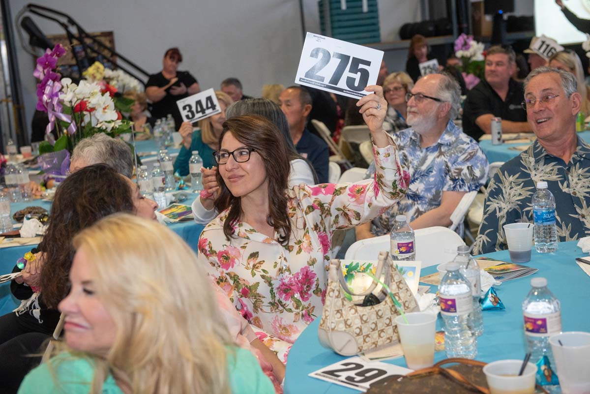 People holding up bidding numbers