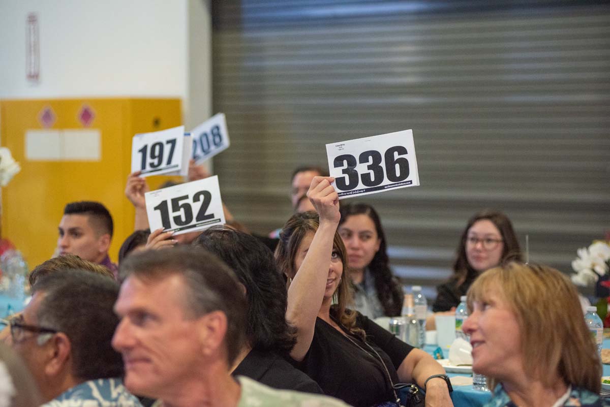 People holding up bidding numbers