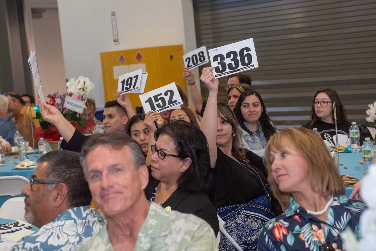 People holding up bidding numbers