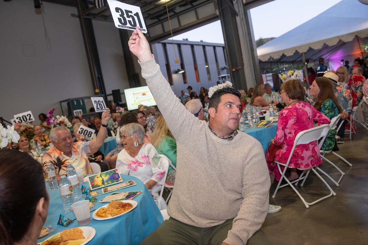 People holding up bidding numbers