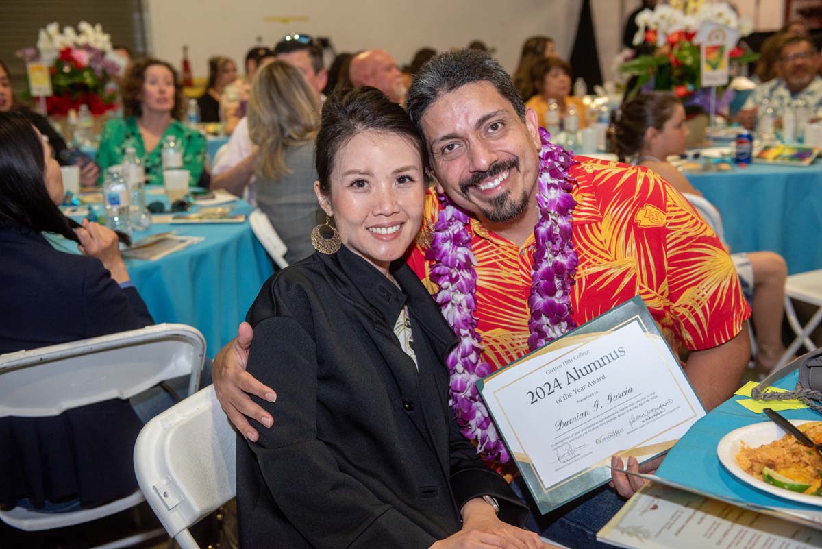 Damian holding certificate, his arm around a woman