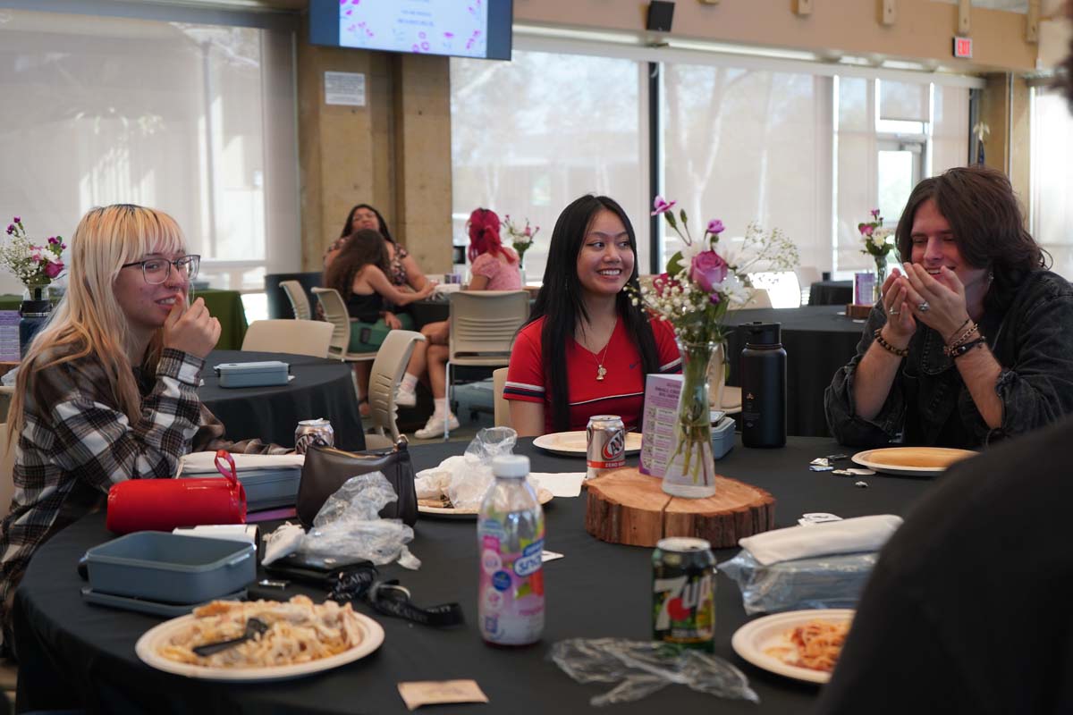 Three people sitting at a table eating at the event
