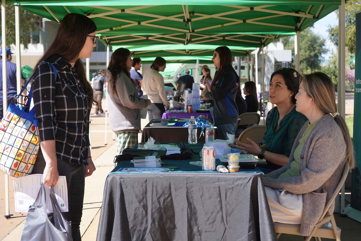Student asking questions at a booth