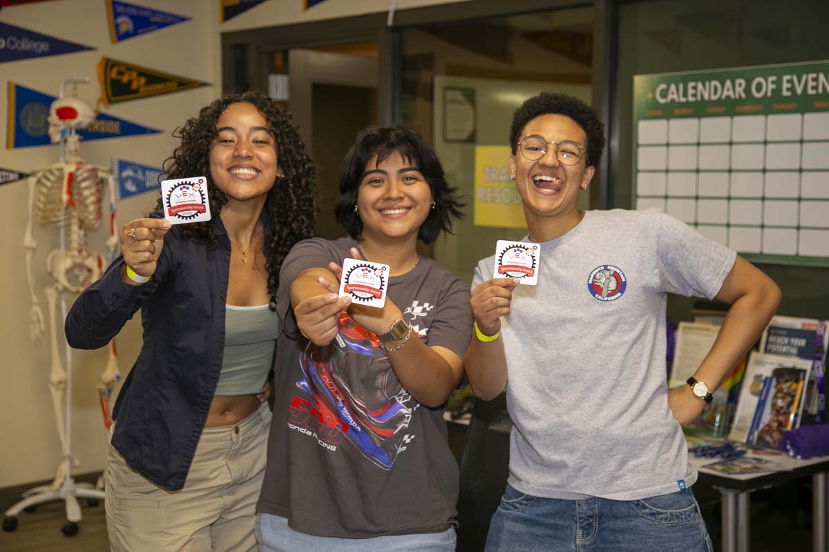 Three Student participants at robotic competition posing with stickers