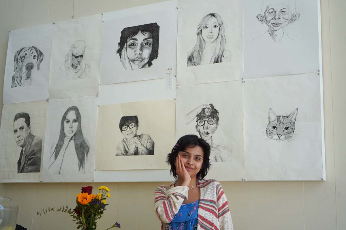 Student posing with her drawings