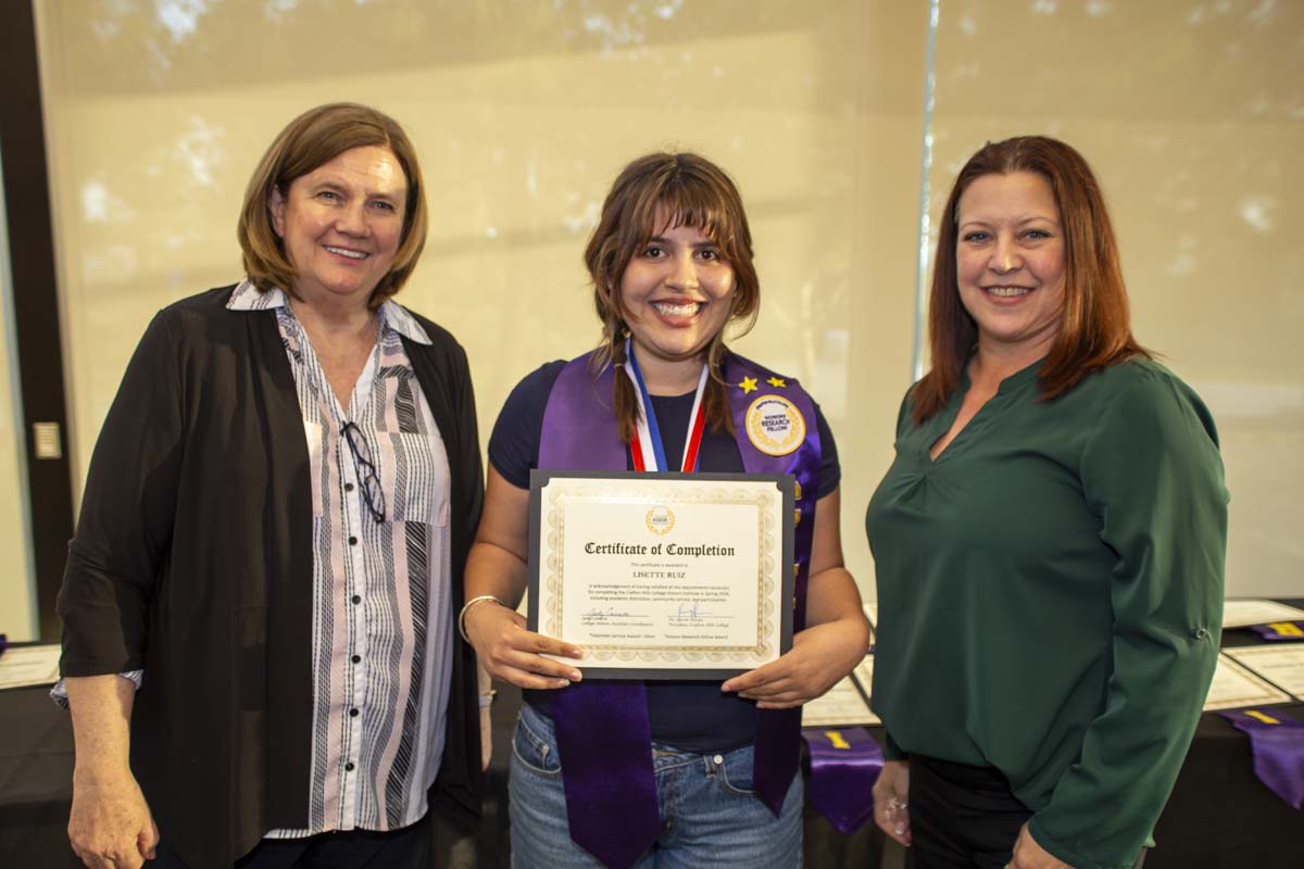 Student posing with a certificate and two faculty members