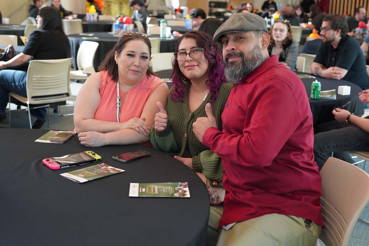 Three people at a table giving thumbs up