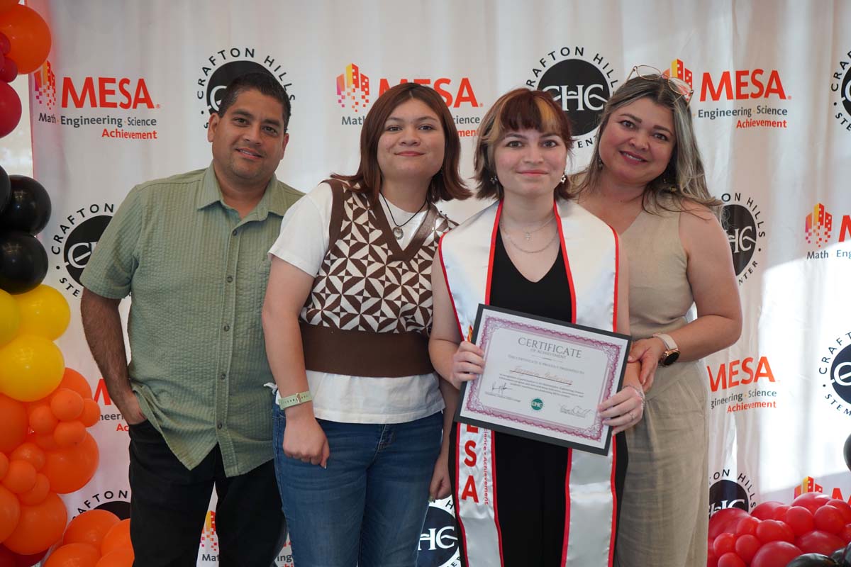 Student with their family in front of the backdrop