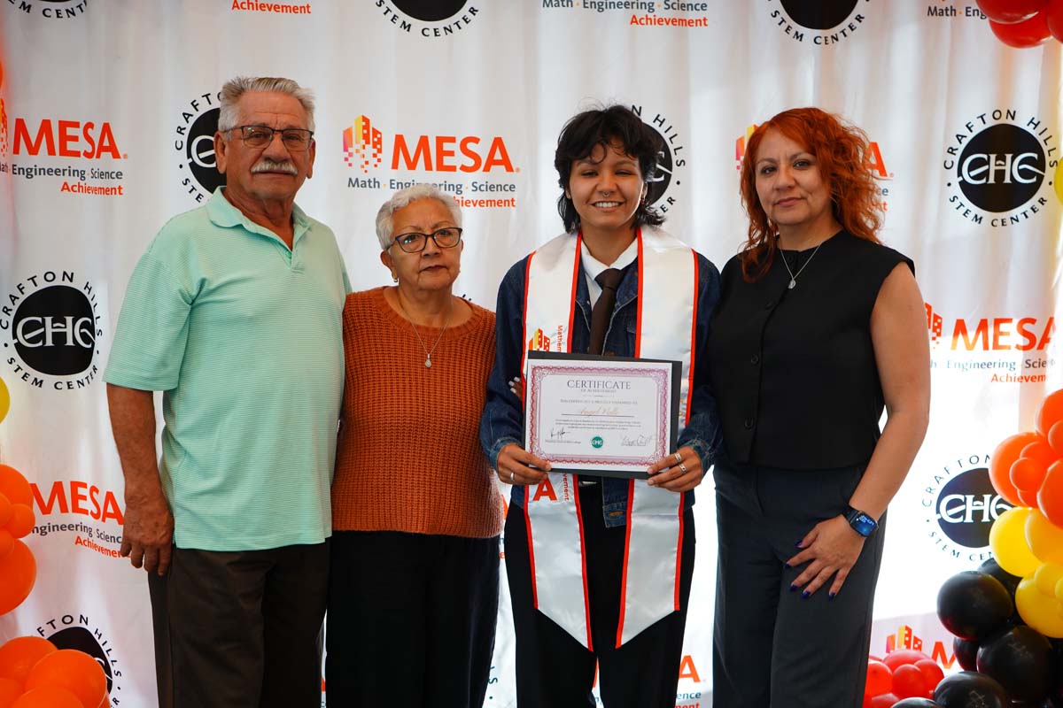 Student with their family in front of the backdrop