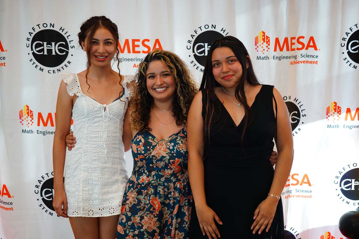 Three students in front of the backdrop