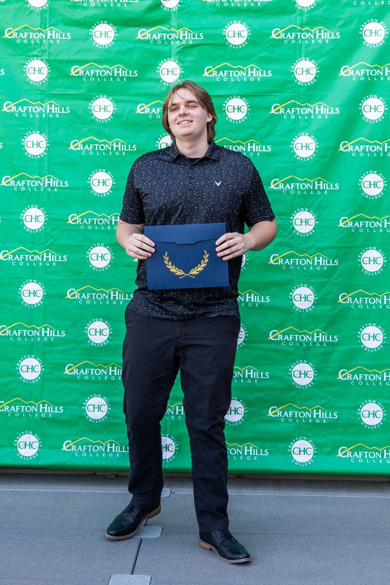Student holding certificate in front of backdrop