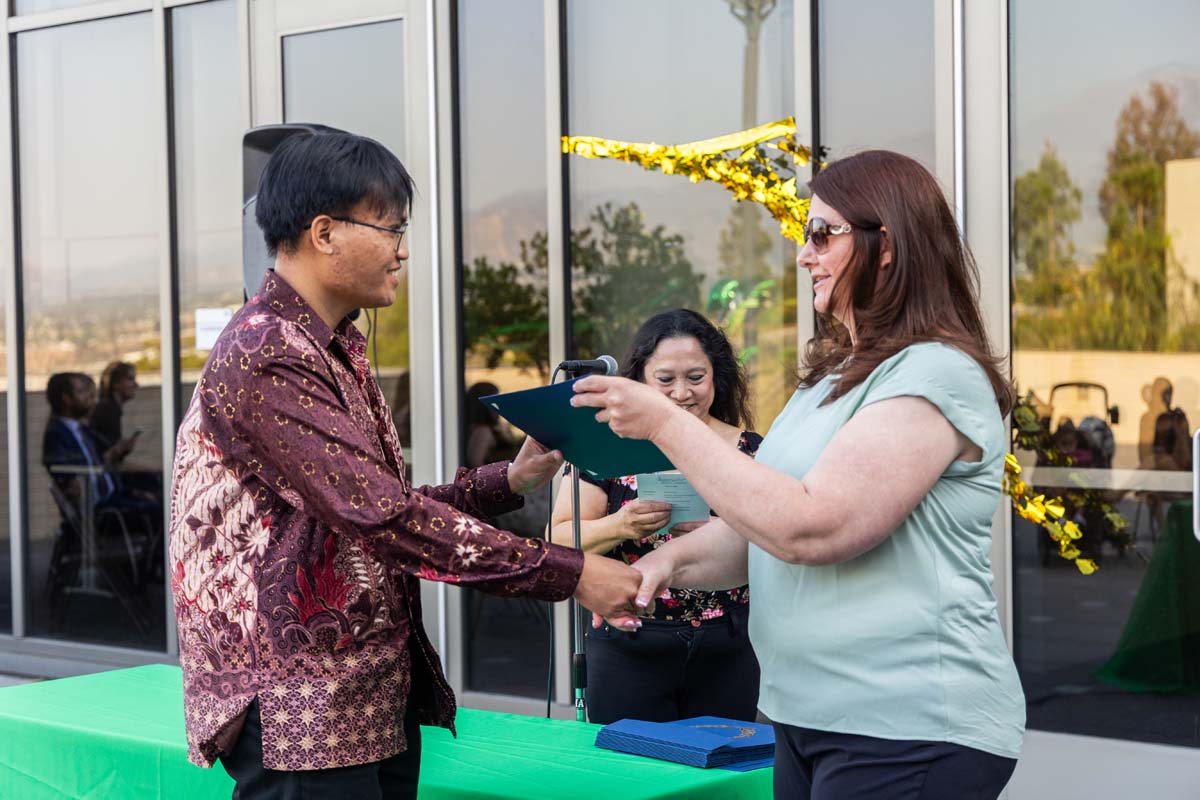 Student grabbing certificate from staff