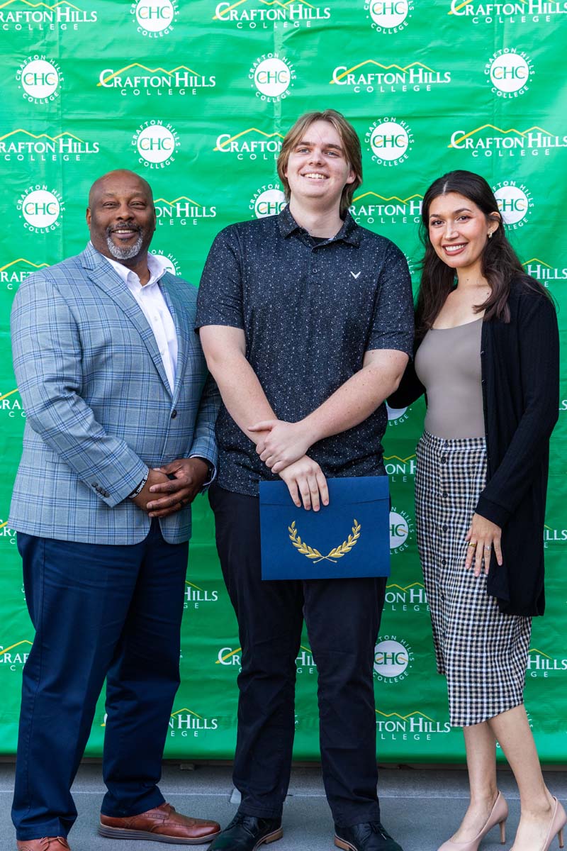 Student and staff posing in front of backdrop
