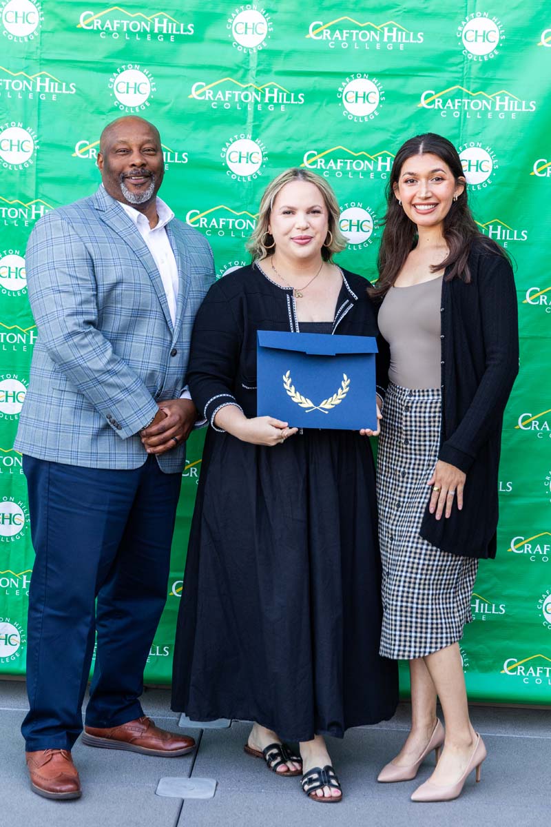 Student and staff posing in front of backdrop