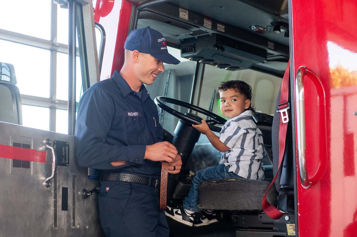 Cadet posing with his child in the fire truck