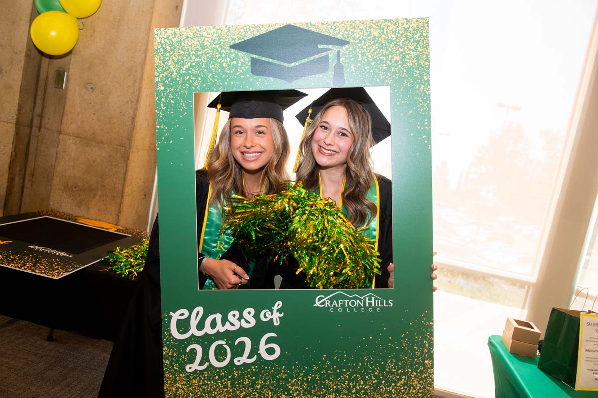 Two graduates posing with a class of 2026 sign