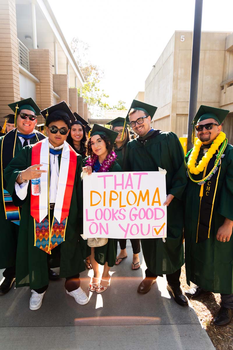 Grad posing with a diploma poster