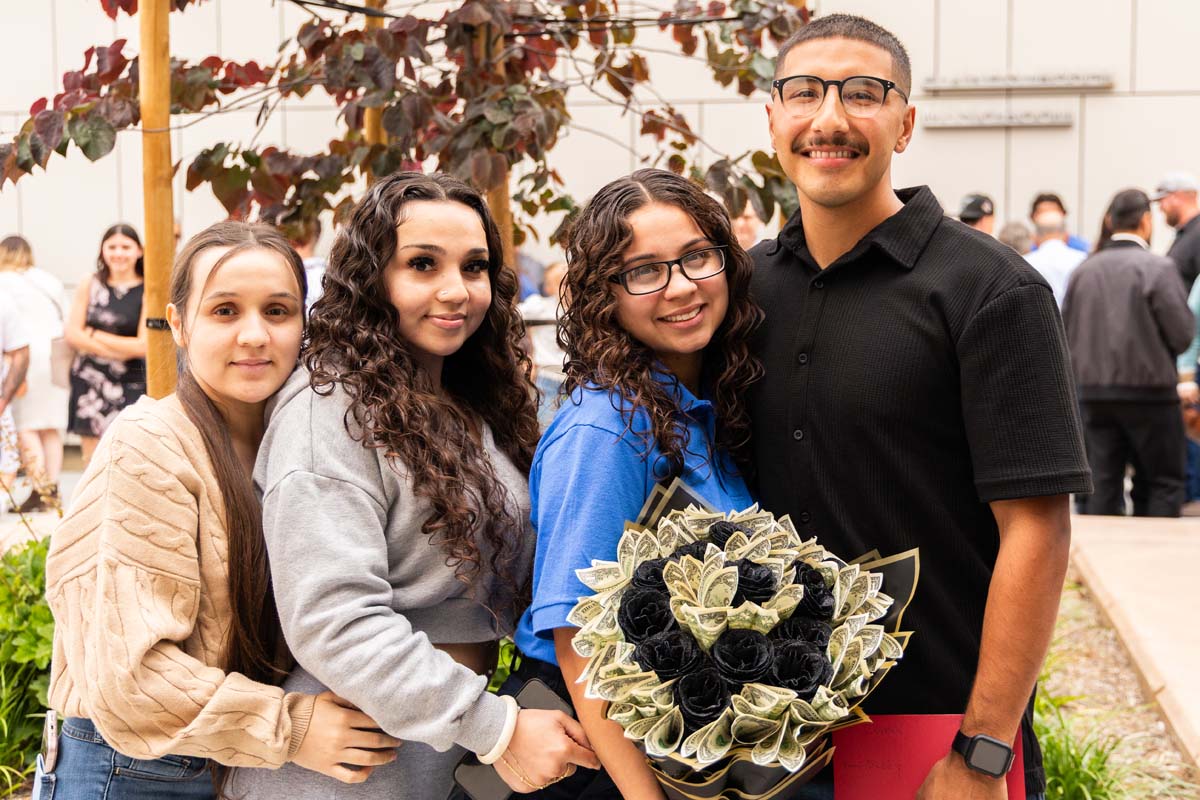 Grad posing with family and flowers