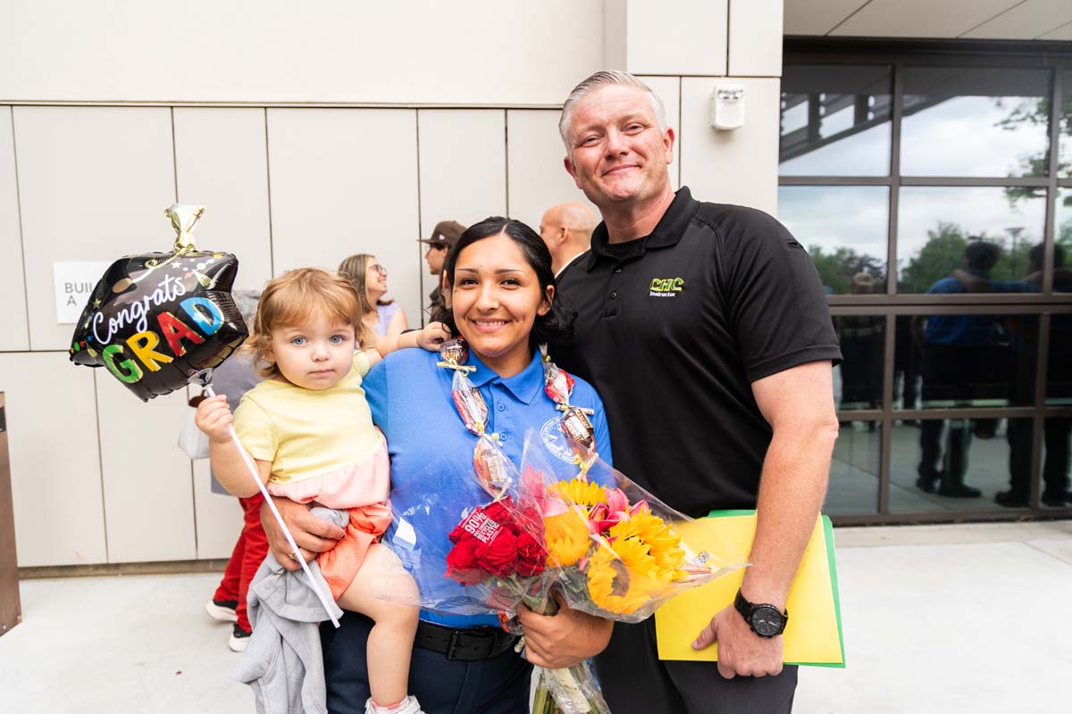 Grad holding balloon posing with family