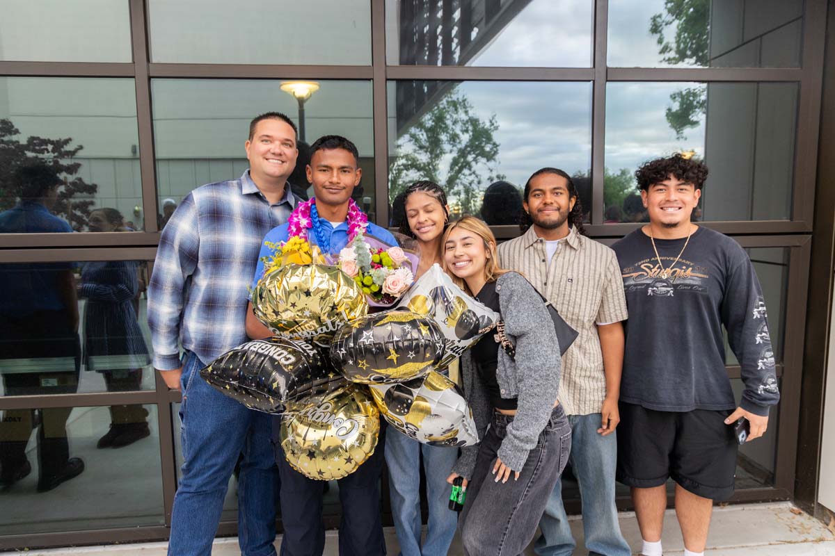 Grad with balloons posing with family