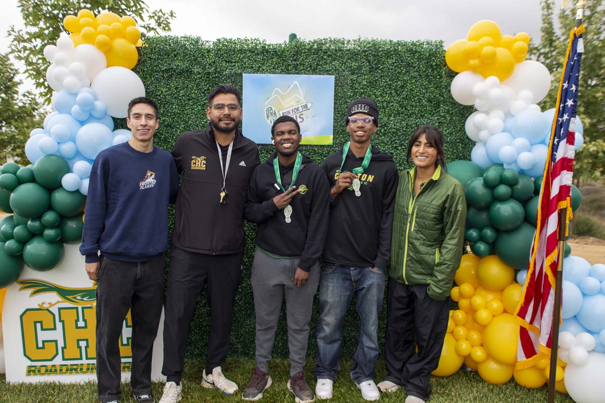 Five people posing in front of the backdrop