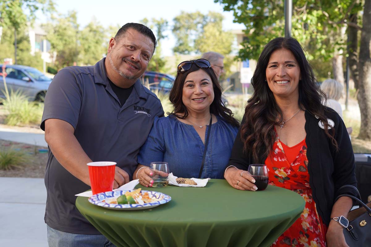 Three people standing at a table