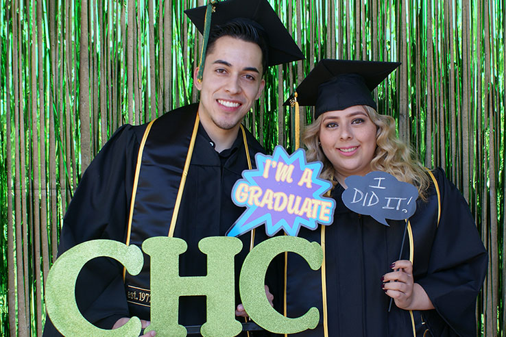 Students in graduation gear holding signs that say, "CHC", "I'm a graduate" and "I did it!"