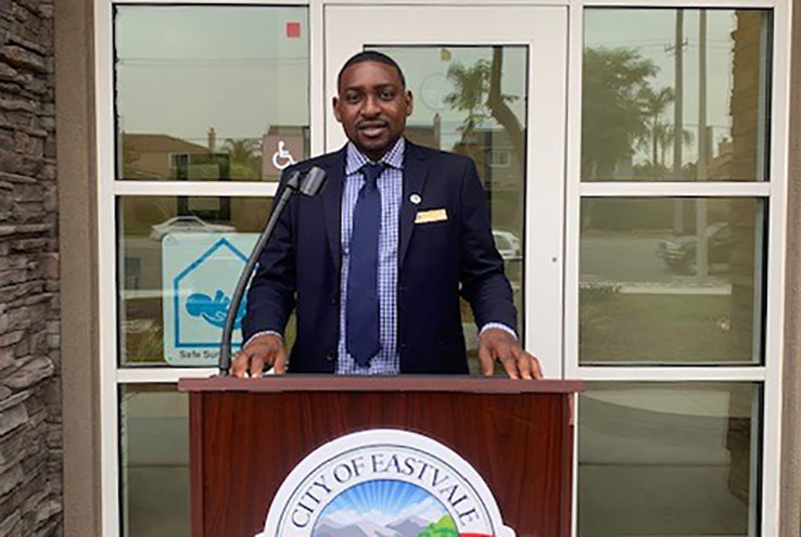 Ibraheem Lawal at the podium in front of the City of Eastvale City Hall building.